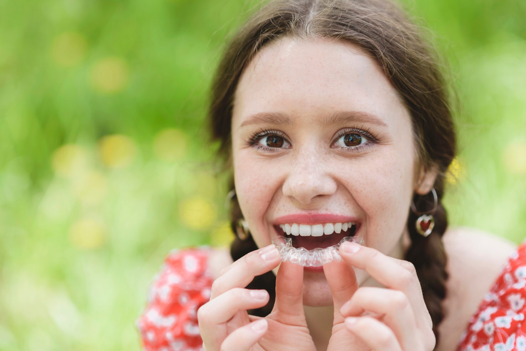 Teenaged girl inserting clear aligners.